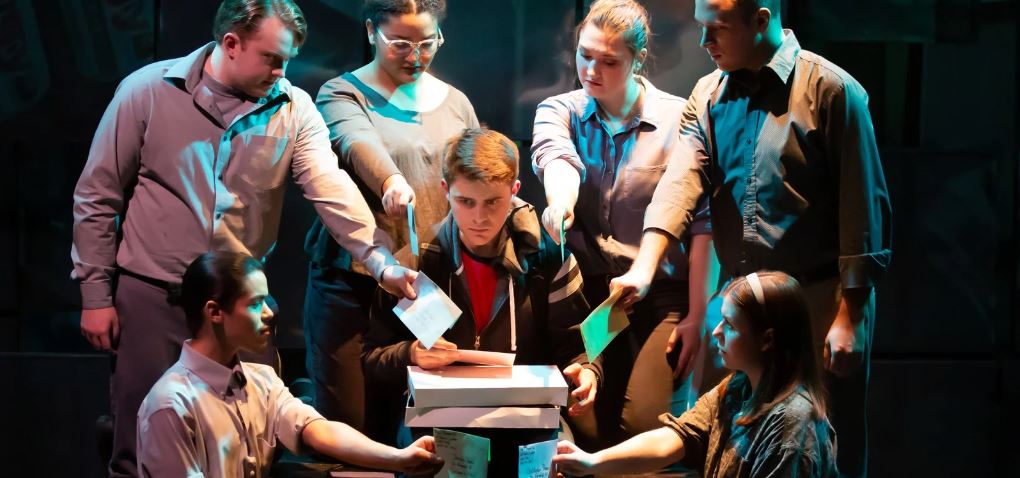 A worried young man surrounded by adults.